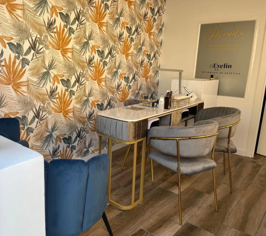Salon de belleza con una silla y mesa, de fondo pared con papel de hojas