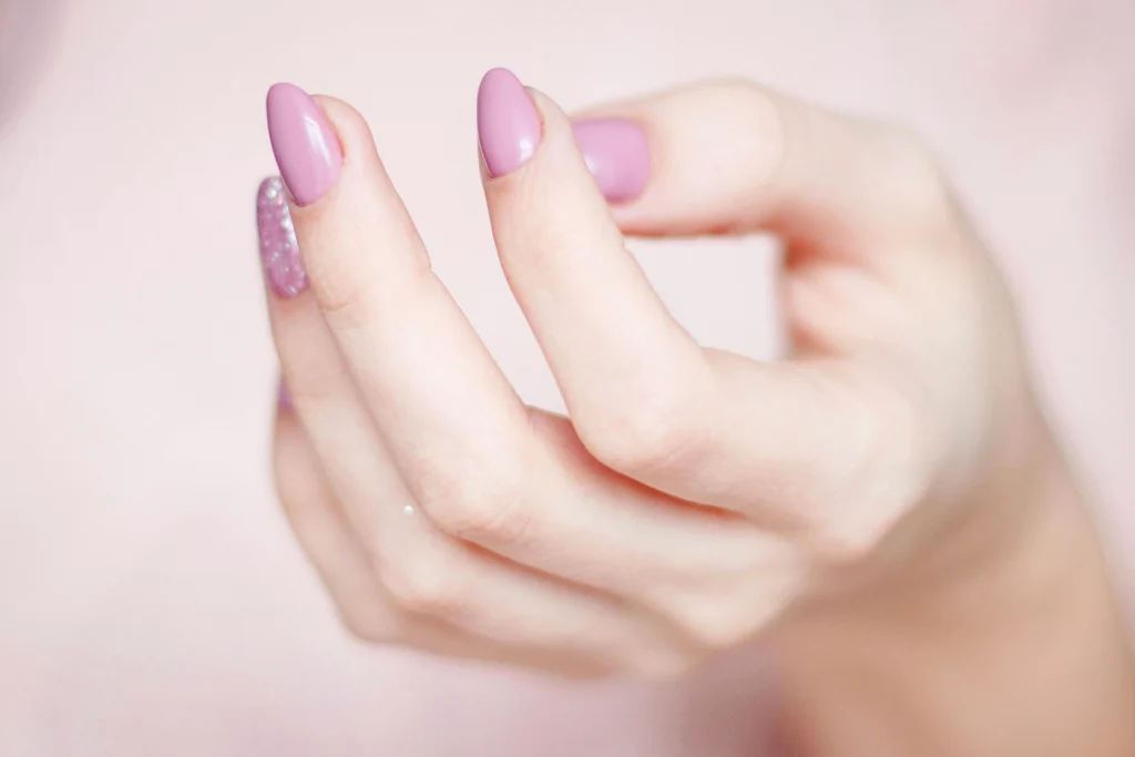 Mano con uñas pintadas en tono rosa