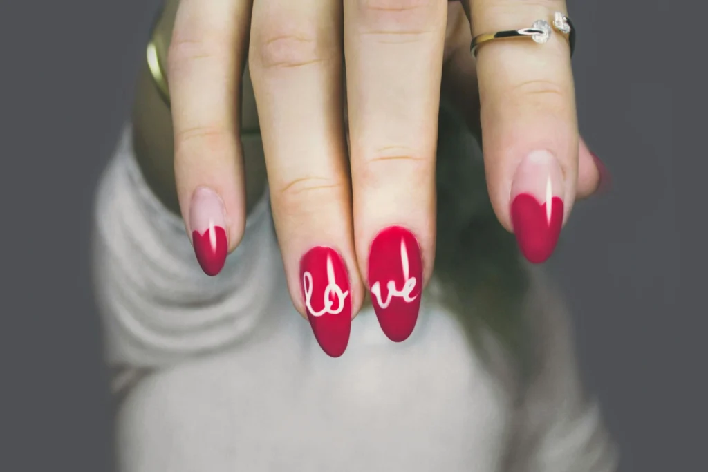 Mano de mujer con uñas pintadas en rojo con la palabra love